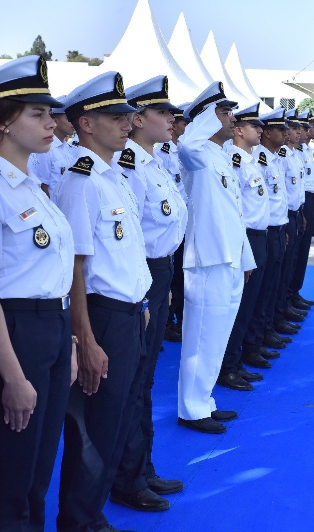 Several individuals are working on a boat or small vessel on a wooden deck, overlooking the ocean. The atmosphere suggests a maritime setting with the presence of equipment, possibly for survey or research. The sign indicates a survey buoy, suggesting a scientific or technical purpose.